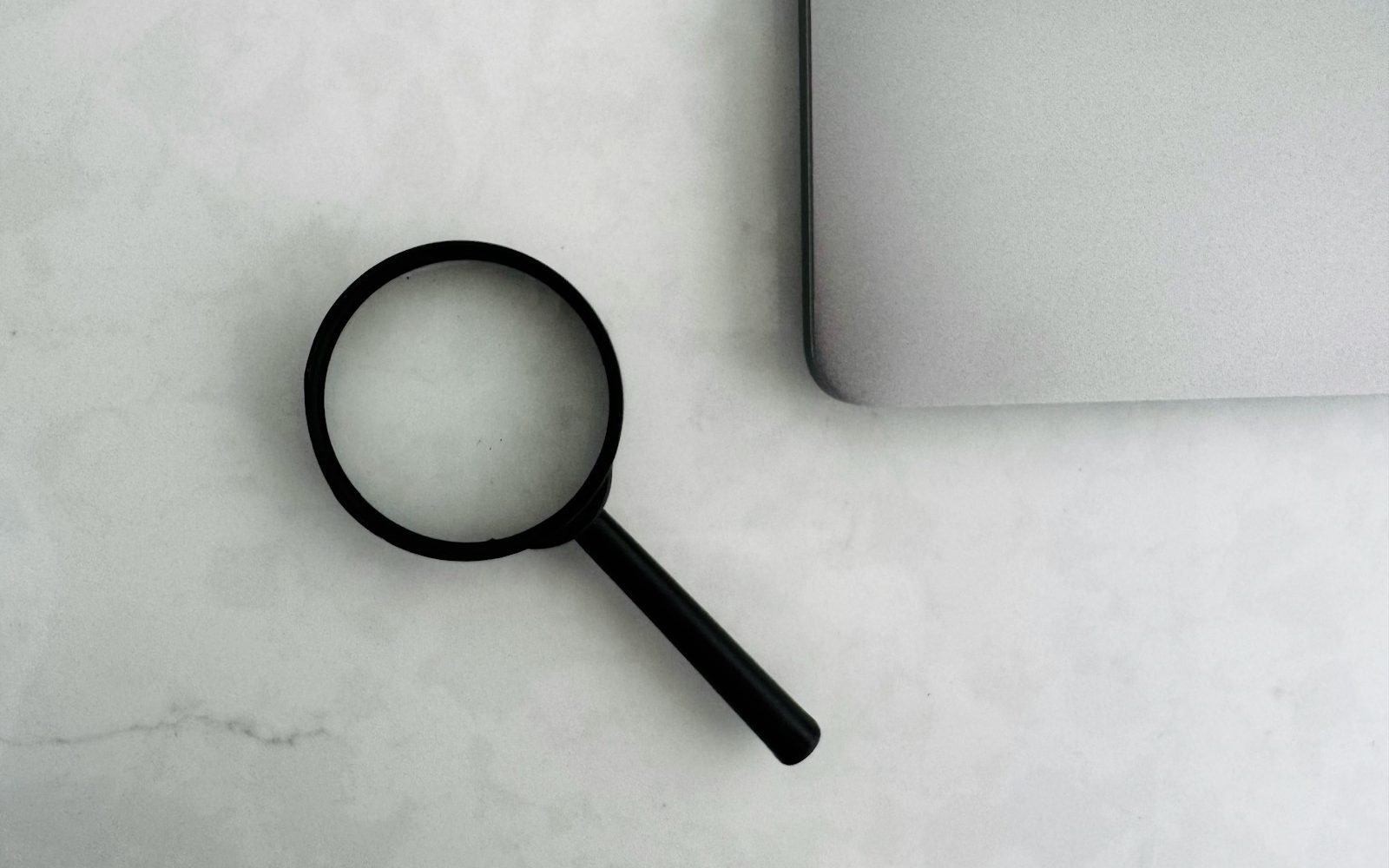 Lupa apoyada junto a una laptop sobre una mesa