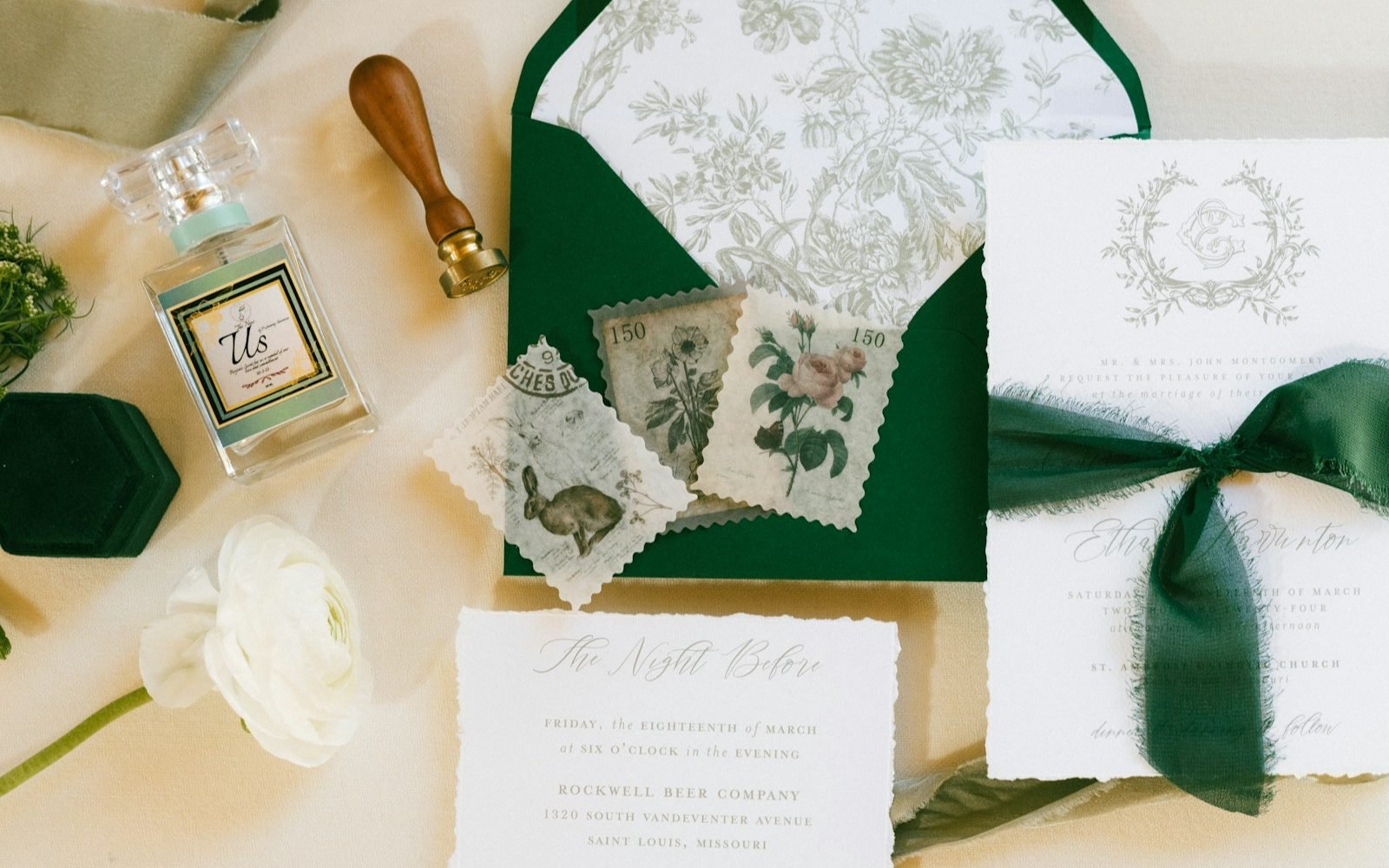 Juego de papelería de boda con sobre verde, sellos de cera y flores sobre una mesa