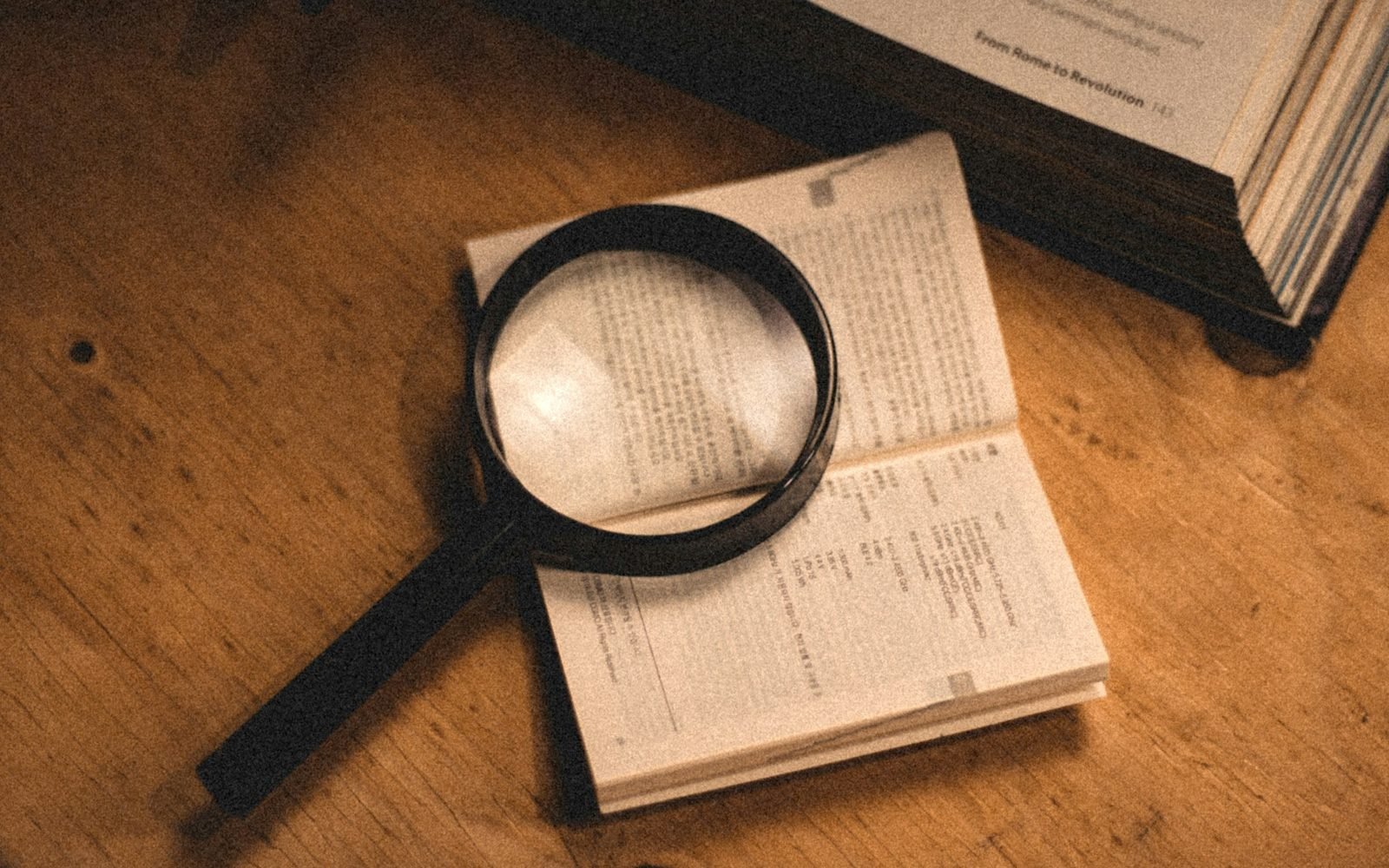 Lupa sobre las páginas de un libro abierto en una mesa de madera