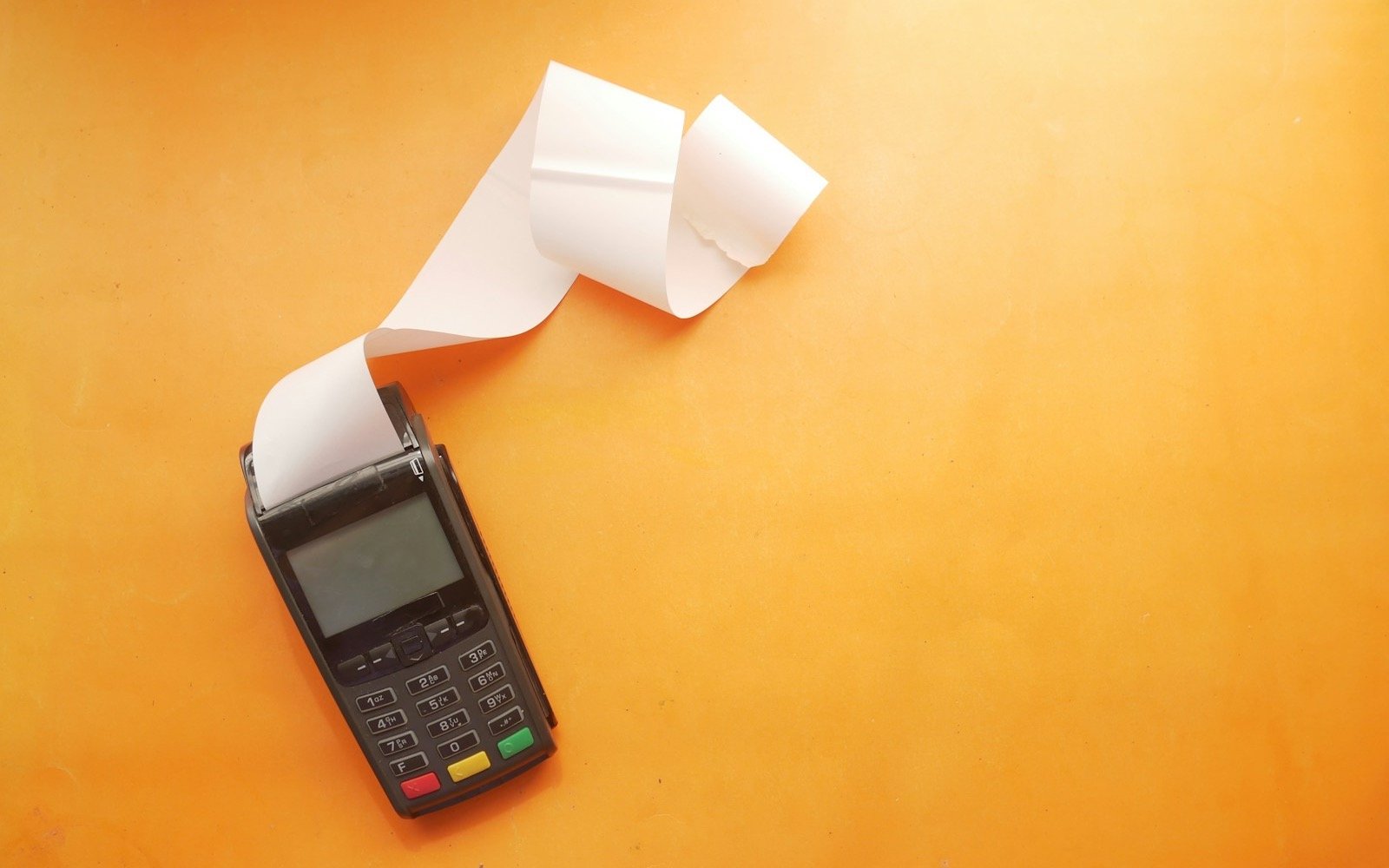 Terminal de pago sin contacto sobre una superficie naranja. Foto: Towfiqu barbhuiya, Unsplash