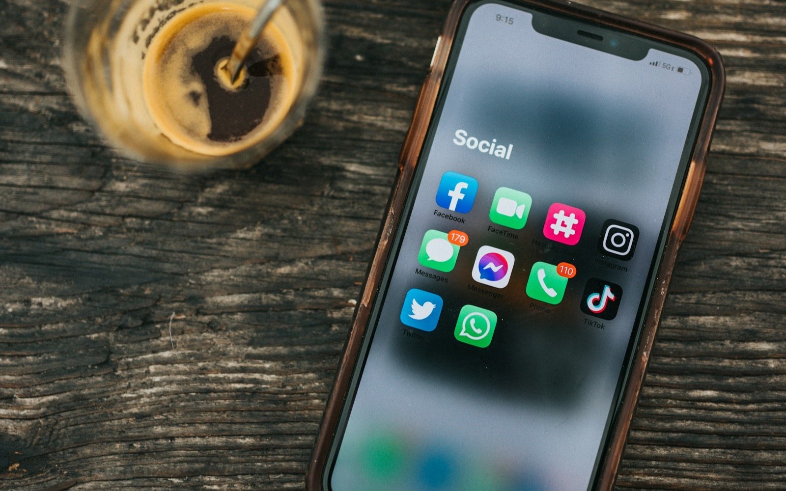 Teléfono con aplicaciones de redes sociales junto a un vaso de café. Foto: Nathan Dumlao, Unsplash