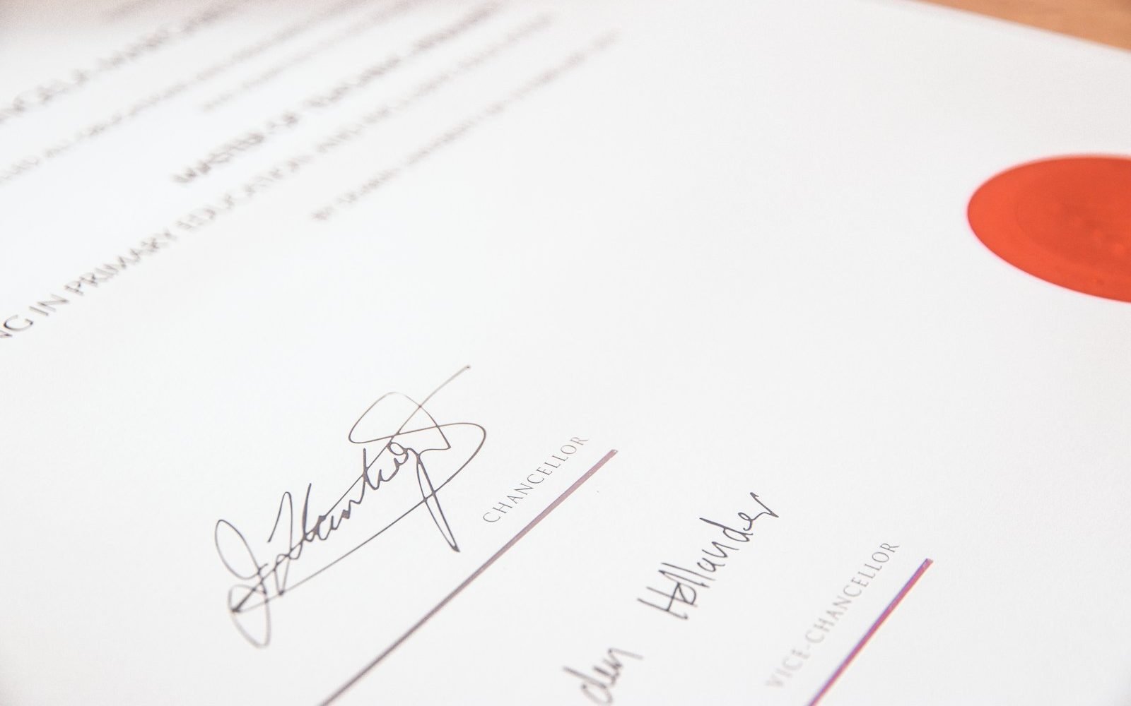 Documento oficial con sello rojo y dos firmas sobre un escritorio. Foto: Lewis Keegan, Unsplash